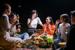 © Wasana - A group of people are sitting around a table with food and drinks
