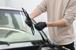 © Mihail - A person is changing car wiper blades while wearing gloves to ensure cleanliness and safety in a garage workspace.