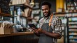 © Nazmul - Barista in Business: A friendly barista in an apron smiling while looking at the tablet, representing small business and a service worker in coffee shop, standing at the front of the business.