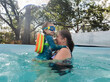 © Austockphoto - Toddler swimming in water of backyard pool with grandmother on summers day