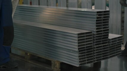 Poster - A skilled worker carefully transports aluminum components for assembly, focusing on precision and quality in the semi-trailer manufacturing process.