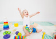 © inna717 - A 5-7 month old baby sits on the floor and plays with bright toys in his room.