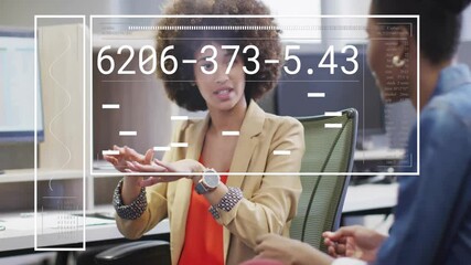 Poster - Two colleagues discussing across desk in business office, showing floating data charts and numbers