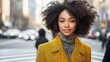 © Irina Kozel - A fashionable Black woman with natural hair wears a stylish yellow coat and stands confidently in an urban street setting