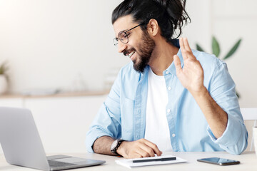 Poster - Online Communication. Young Eastern Guy Making Video Call With Laptop At Home, Sitting At Desk And Waving Hand On Camera, Handsome Arab Man Greeting Somebody During Web Conference, Copy Space