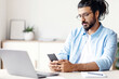 © Prostock-studio - Pensive Arab Freelancer Man Messaging On Smartphone While Sitting At Desk In Home Office, Having Break In Work, Young Eastern Guy Using Cellphone, Browsing Internet Or Checking Social Networks