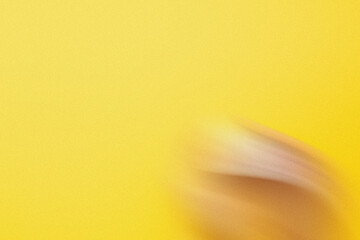 Poster - A blurred image of a hand pointing towards a bright yellow background creating a sense of minimalist art