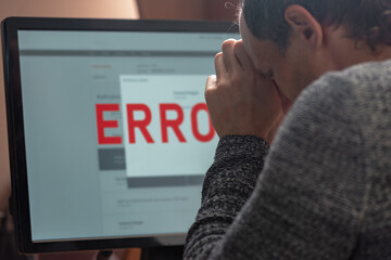 Poster - Man using computer with application error message on screen. Man experiencing frustration as he looks at an error message on his computer screen, showcasing his emotional reaction