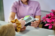 © ADDICTIVE STOCK - A client hands over a payment card to the cashier at a beauty salon