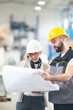 © Aleksandar - Engineers in factory checking plans, smilling and talking