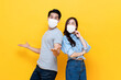 © Atstock Productions - Carefree young Asian couple wearing face mask in isolated yellow color background studio shot