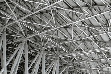 Poster - Ceiling of industrial building bottom view. Hangar made of metal structures. Interior of industrial building. Columns of steel beams take up roof of hangar. Warehouse interior made of metal elements