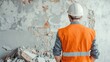 © Nat_Photo_AI - Construction Worker in Orange Vest with Hard Hat Observing Demolition Site with Exposed Brick Wall