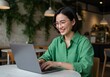 © Pixelpulse Creative  - Smiling woman works on laptop at cafe table, green shirt, glasses