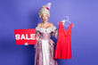 © deagreez - Elegant woman in a historical gown with sale sign and red dress on purple background portraying vintage fashion style