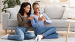 © Prostock-studio - Happy black ladies using new mobile app while resting at home together, free space. Two cheerful african american sisters checking social media on smartphone, sitting on floor at living room