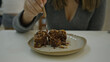 © Krakenimages.com - Woman enjoying dessert in luxurious modern restaurant cafeteria, showcasing elegance and culinary delight with chocolate brownie and fork close-up.