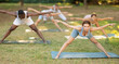© JackF - Yoga female coach conduct rehearsal for multinational followers in park, leading of performing exercises, do fulfil Prasarita Padottanasana. People practice sport during yoga workout in nature