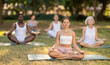 © JackF - Yoga female coach conduct rehearsal for multinational followers in park, leading of performing exercises, do fulfil padmasana, svastikasana. People practice sport during yoga workout in nature