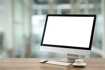 Aufkleber - Computer monitor with blank screen and cup on wooden desk against blurred background. Mockup for design