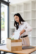 © David - Business woman with box cardboard packing personal items after losing jobs. asian business woman standing on office background. Your fired Unemployed Jobless People Crisis