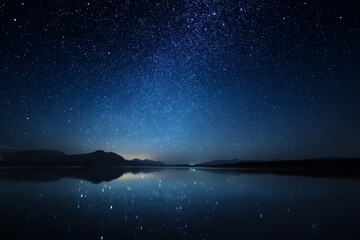 Poster - breathtaking night sky filled with stars reflects on calm lake, creating serene and mesmerizing natural spectacle