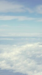 Wall Mural - Vertical shot of Above the clouds, the airplane reveals a serene skyscape, blending white clouds and blue horizon during a flight. Suitable for serene travel or nature themes.