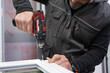 © oscar - Carpenter using cordless drill assembling aluminum window frame