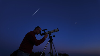 Wall Mural - amateur astronomer looking at the evening skies, observing planets, stars, moon and other celestial 