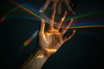 Poster - Captivating Hand Silhouette Embracing Colorful Light Reflection in Dark Setting