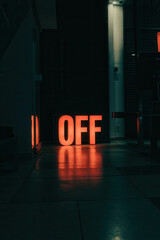 Poster - Illuminated 'OFF' Sign in Dimly Lit Space with Reflective Floor and Urban Ambiance