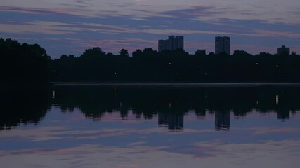 Fototapete - Beautiful sunset over city skyline reflecting on calm water