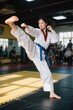 © haiqiang - woman in white karate outfit kicking a kick in a gym