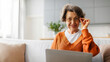 © Home-stock - Portrait of smiling senior woman sitting on couch with laptop, looking at camera with smile, panorama with free space. Retired people technology concept