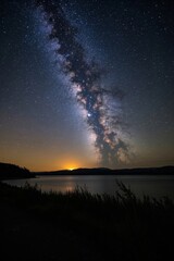 Wall Mural - milky over a lake with a bright orange glow in the distance