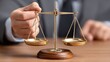 © Jack - A close up of a businessmanâ€™s hands in cufflinks gently balancing scales of justice on a polished wood desk for law firm marketing and legal consulting visuals