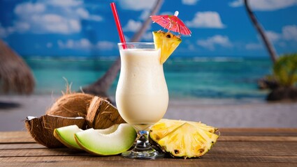 Aufkleber - A tropical drink with coconut and pineapple on a table in front of a beach scene backdrop.