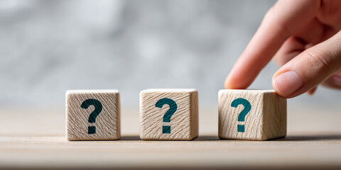 Poster - Three wooden cubes with question marks, a finger lightly touching one, suggesting decision-making or problem-solving
