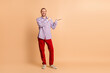 © deagreez - Young man with beard gesturing towards empty space in casual outfit on beige background showcasing a positive atmosphere