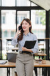 © Kritdanai - Smiling Asian Businesswoman Talking on Phone in Office