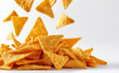 © Curioso.Photography - Golden tortilla chips falling and piling up on a clean white surface with a dynamic sense of motion.