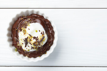 Wall Mural - tasty chocolate pudding with whipped cream in bowl on white wooden table, top view. space for text