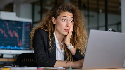 Poster - Worried Businesswoman: A young businesswoman looks worried while working on her laptop in a modern office.  The image conveys stress, concern, and the pressure of the corporate world.