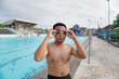© Yazid Nasuha - Shirtless Asian man preparing to swim, wearing goggles in public pool