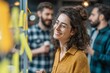© Роман Булатов - Young businesswoman brainstorming ideas with colleagues on glass board using sticky notes in modern office space