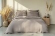 © Ponimah - Gray linen duvet cover set on a bed, minimalist and neutral  Natural light streams in, illuminating the room  Dried pampas grass and decorative vases complete the simple aesthetic