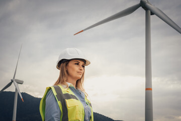 Poster - A determined female engineer in a hard hat and reflective vest stands proudly at a wind farm, symbolizing the empowering spirit of renewable energy and the innovation in engineering