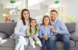 © Studio Romantic - Happy loving family portrait, smiling bonding mother and father with two little children posing at home, looking at camera, family enjoying moment, children having fun together in modern living room