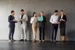 © Studio Romantic - Full length portrait of business people men and women in formal clothes talking on a meeting indoors. Company employees team standing in a row on gray wall background communicating with each other.