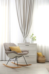 Poster - Rocking chair and chest of drawers near window with stylish curtains in living room. Interior design